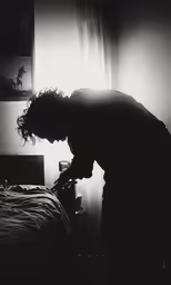 a man leaning over while looking down at his bed