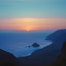 sunset over some hills and the ocean