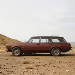 a vintage maroon car is parked in the desert