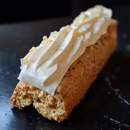 closeup of a pastry with cream frosting and walnuts