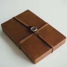 a brown journal with a watch on it