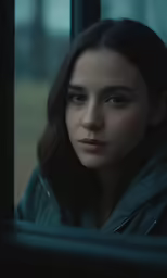 a woman sitting behind a window with her eyes wide open