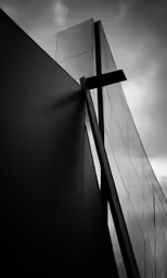 a black and white photo of the side of a building with a cross