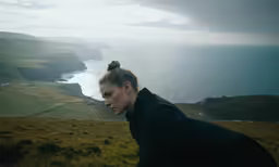 a woman standing in front of an ocean with her head down