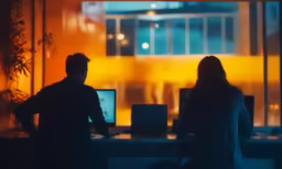 a man and woman are looking at a monitor