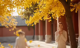 two people are walking past trees and in a courtyard