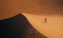 a lone man is running across a sand dune