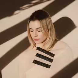 a woman standing by a shadow wall