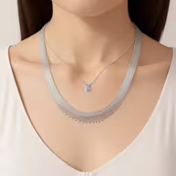 a female mannequin wearing a silver necklace with an oval shaped diamond and bead detail,this is a woman wearing an elegant silver necklace,a close up of a model wearing silver chain and necklaces,a female in a white shirt wearing a silver chain necklace,a woman wearing a silver necklace and a diamond pendant