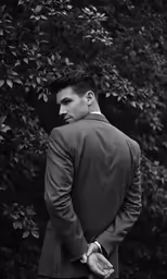 a man standing in front of a tree looking over his shoulder