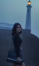 a woman is walking away from the light house