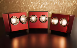 three red speaker on a table with some lights