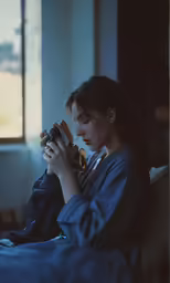 a woman using her cell phone while sitting on a bed