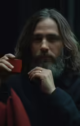 a man with long hair is holding a small cup