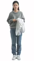young woman standing holding clothing on white background,a woman standing with a pile of clothing