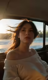a woman sitting in the passenger seat of a car looking out at the sun