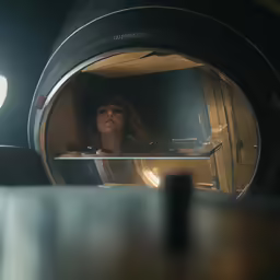 a girl is sitting in the mirror looking into a telescope