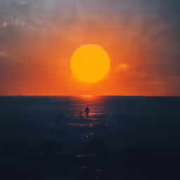 a silhouette of a person standing in the ocean at sunset