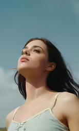 a beautiful young woman in a grey top looks up into the sky