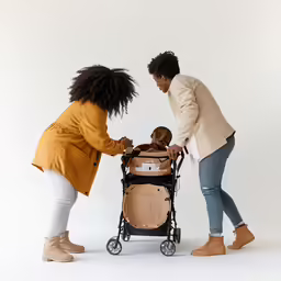 two women pushing a small child in a stroller