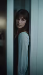 woman standing next to a white door with light on