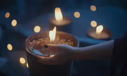 a person holding a lit candle in their hand