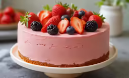 a pink cake is decorated with fruit on it