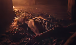 a young woman laying on the ground in a dark forest