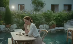 a woman sitting at a table with her hand on her face