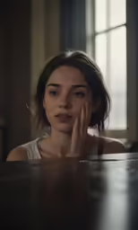 a woman sits at a table in front of a window