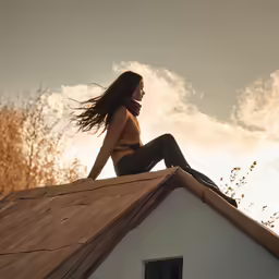 a woman with long hair sitting on the roof of a house