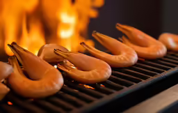 several cooked shrimp being placed on a grill