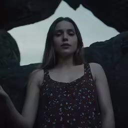 the girl is standing in front of a rock formation