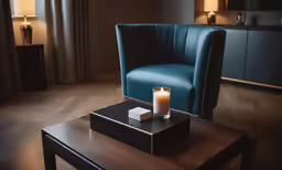 a single candle sits on a table with a small black box next to it