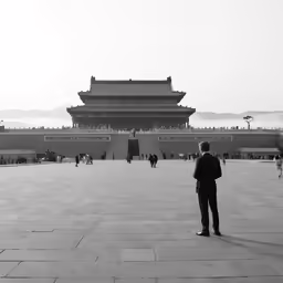 a man looks down at the surrounding courtyard of an asian building