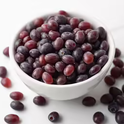 grapes in a white bowl surrounded by other berries