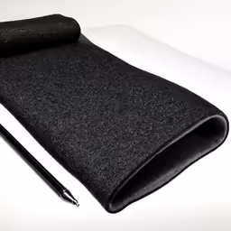 a pen sits atop a black cloth beside a sheet of paper