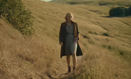a person walking in some tall grass on a hillside