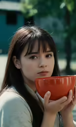the asian girl is holding a cup while looking into the distance