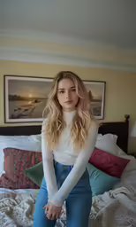 a young woman sitting on her bed posing for a photo