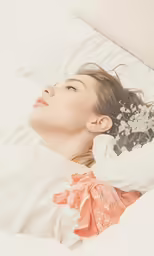 a woman laying on a bed holding a bouquet of flowers