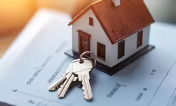 keys to a house on top of documents with the sun shining in