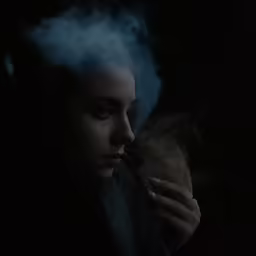 a woman in black clothing smoking and looking into the distance
