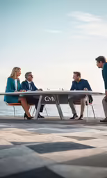 five people sitting at a table talking and looking at something