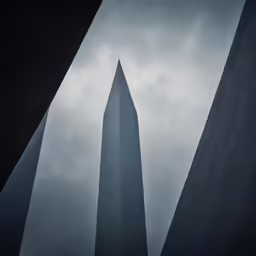 three tall spires rise into the sky above a grey cloudy sky