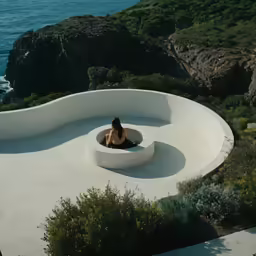 a woman sitting in a circular bed at the ocean