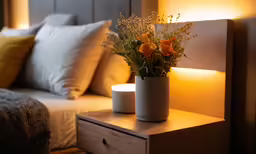 an open nightstand with a vase of flowers on top of it