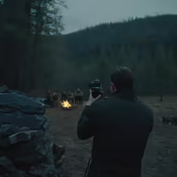 man with camera and a fire in the woods