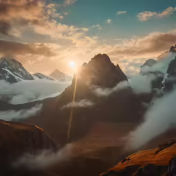 a sunrise behind some snowy mountains and clouds