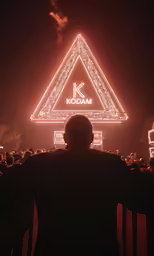 a man standing in front of a tall building that has lights